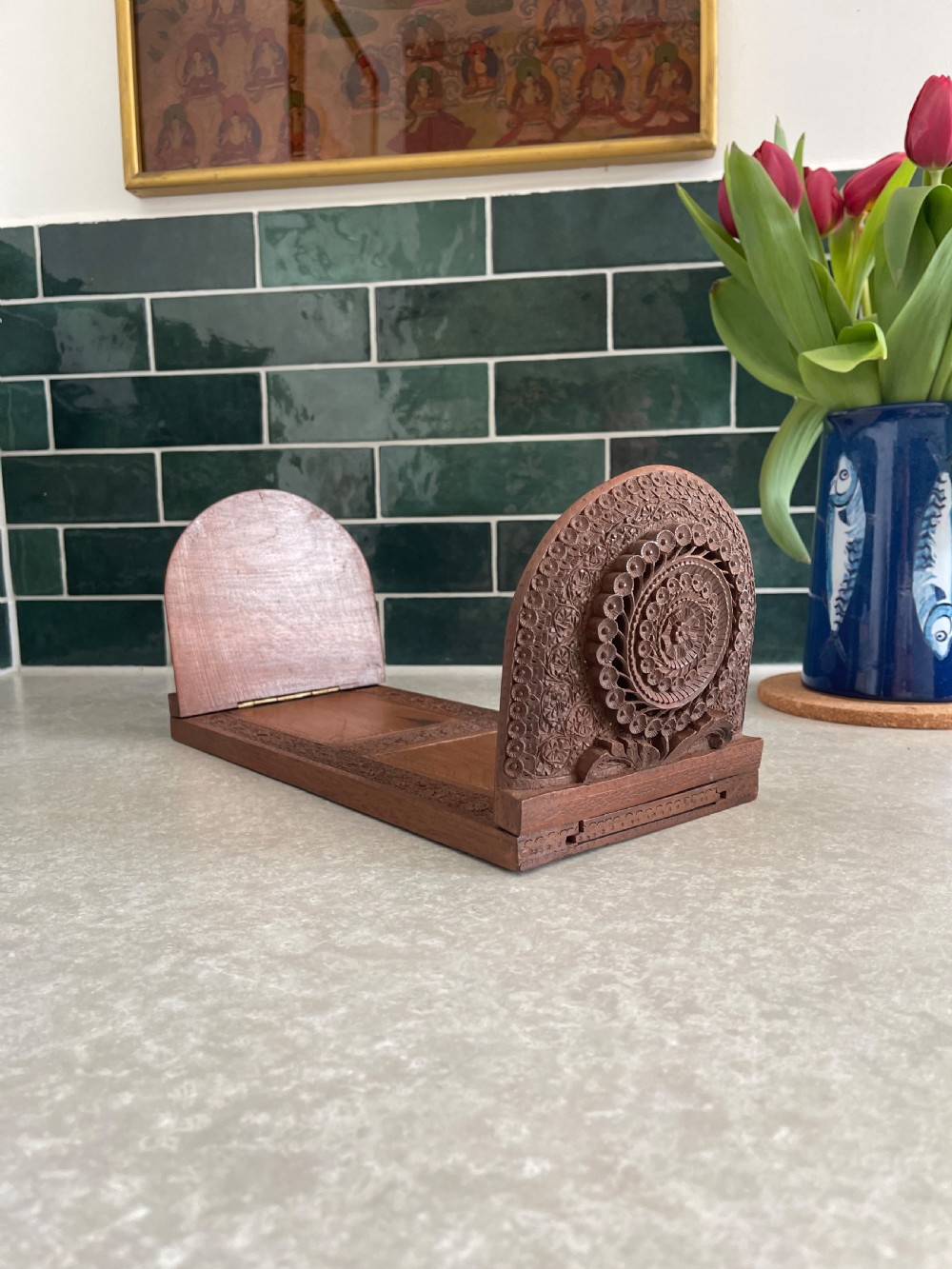 An antique carved warm brown wooden expandable book slide with intricate floral relief carving on arched folding end panels.
