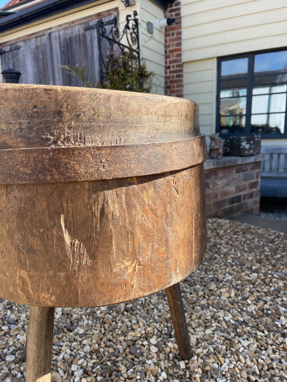 A circular antique wooden butcher block featuring a thick end-grain top set upon three splayed wooden legs. View II
