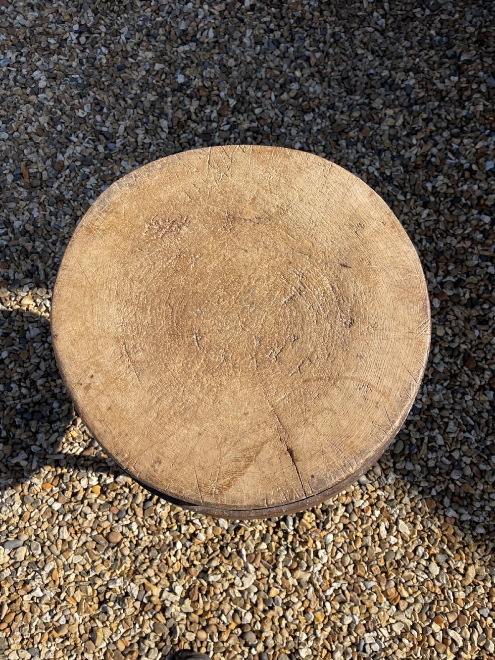 A circular antique wooden butcher block featuring a thick end-grain top set upon three splayed wooden legs. View III