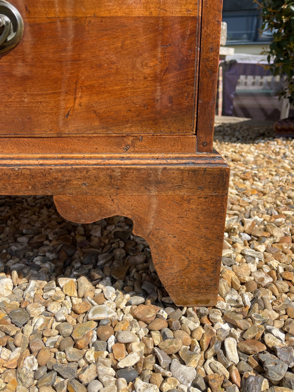 A George III wooden chest of drawers featuring two short drawers over three long graduated drawers, fitted with brass handles and supported on bracket feet. View VI