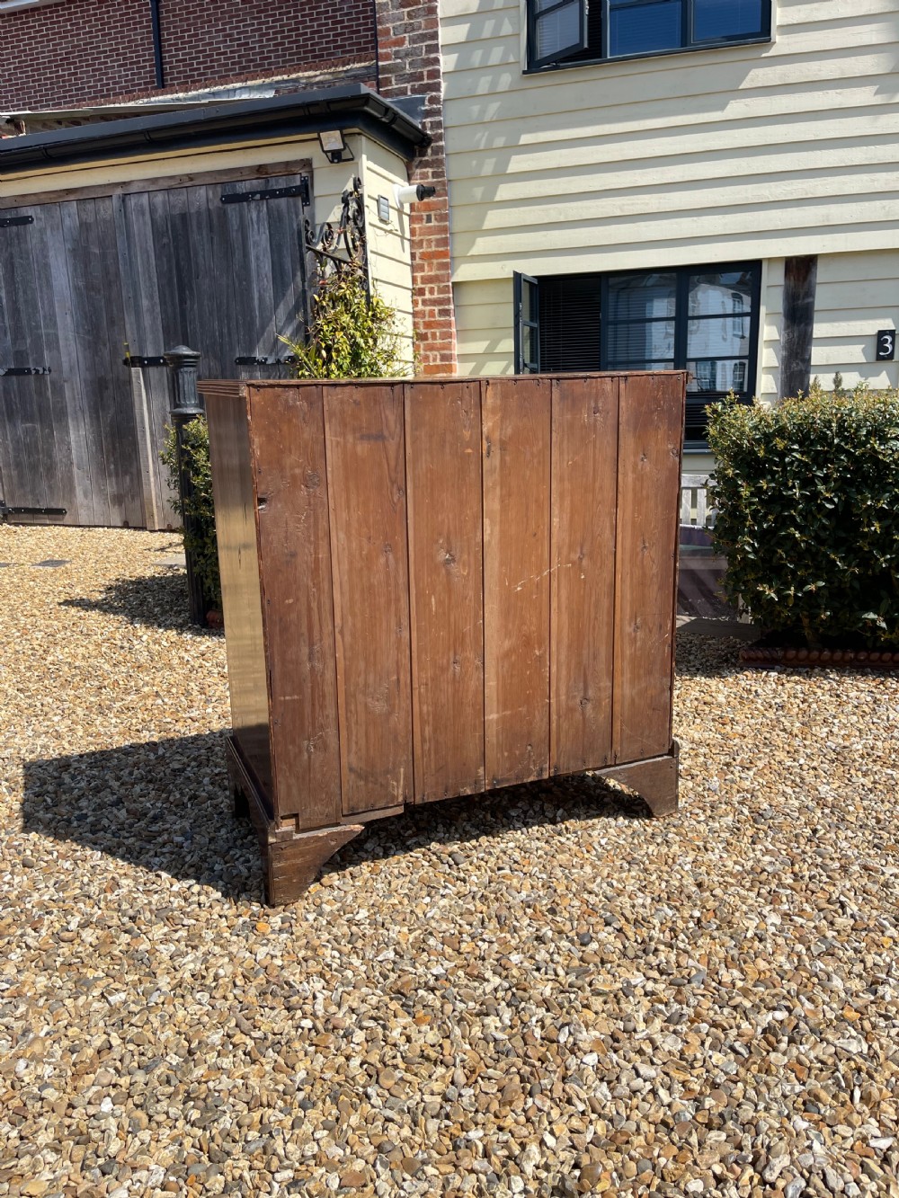 A George III wooden chest of drawers featuring two short drawers over three long graduated drawers, fitted with brass handles and supported on bracket feet. View VII