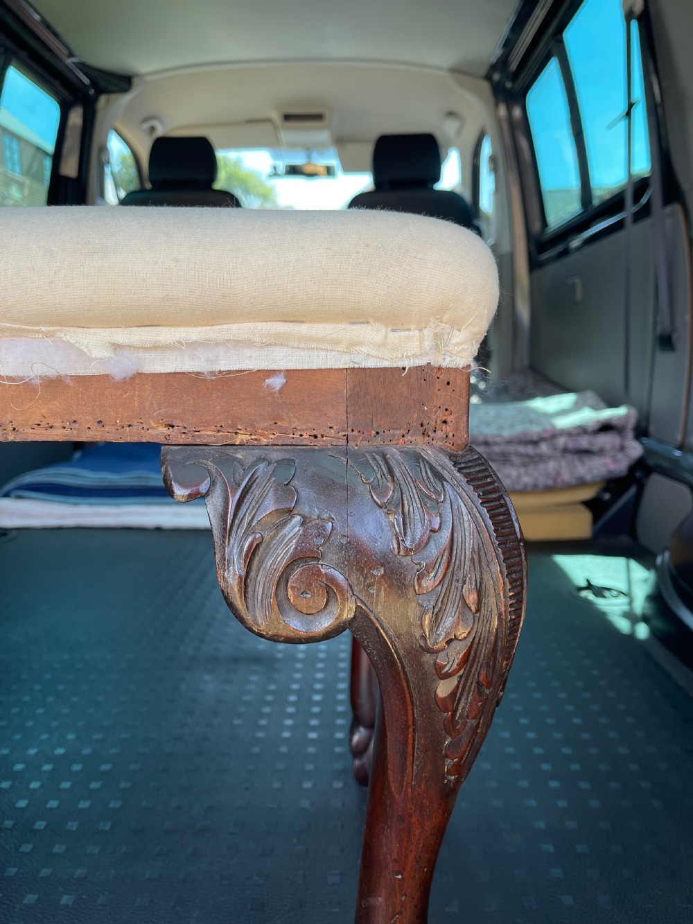 A Georgian style stool with dark carved mahogany cabriole legs ending in ball and claw feet and a padded rectangular seat. View II