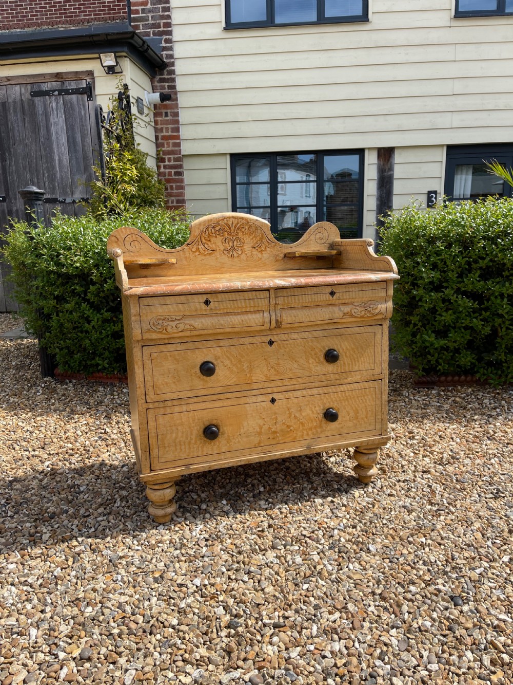 A nineteenth-century pine chest of drawers with scumble paint finish, carved gallery, turned wooden knobs, and turned feet.
