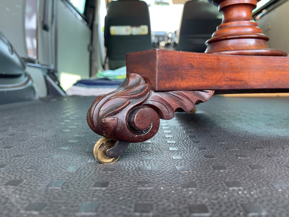 A nineteenth-century mahogany pedestal occasional table featuring a drop-leaf top, fluted central column, and a tri-form base with carved scroll feet on castors. View VII