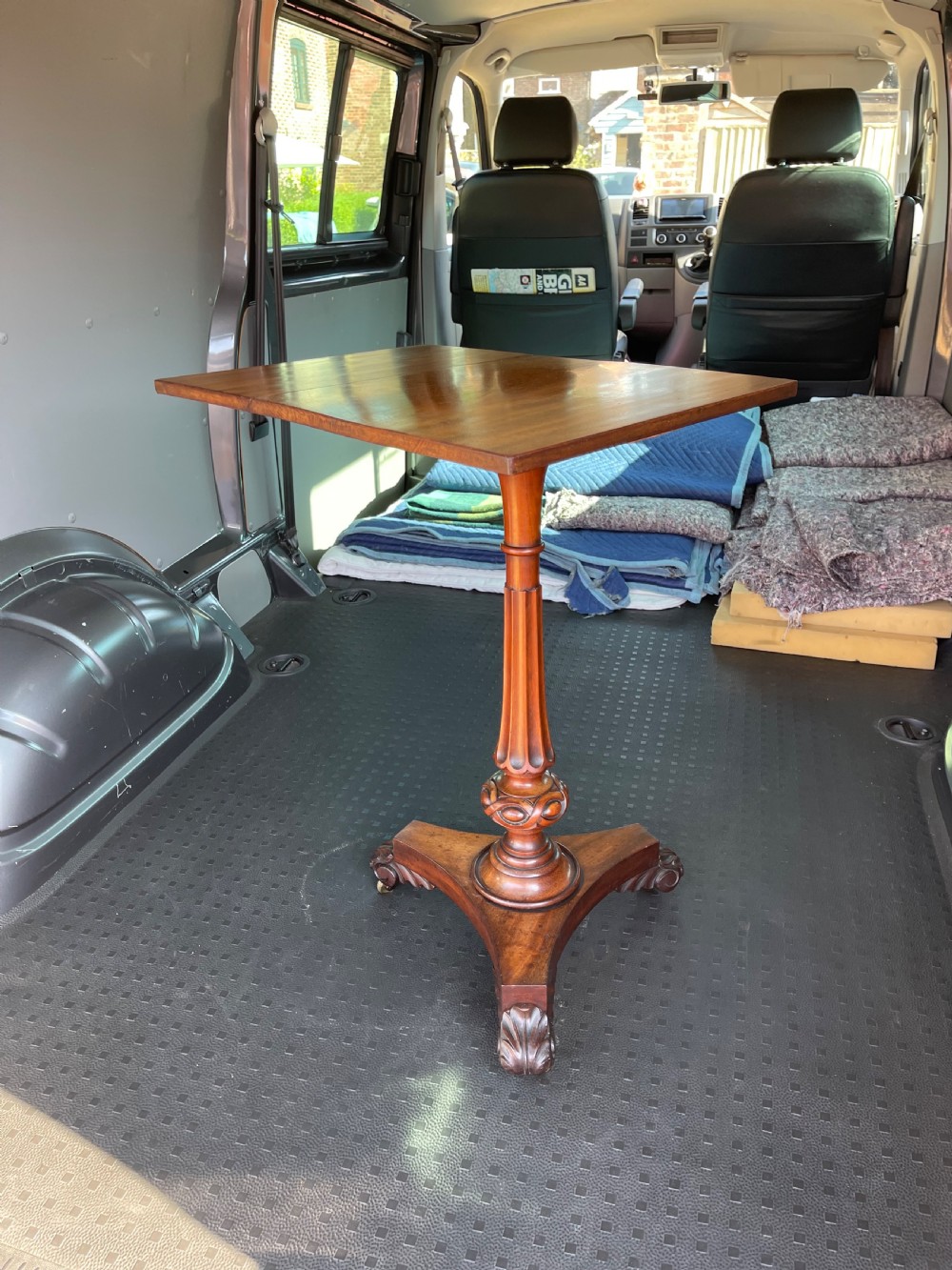 A nineteenth-century mahogany pedestal occasional table featuring a drop-leaf top, fluted central column, and a tri-form base with carved scroll feet on castors. View VIII