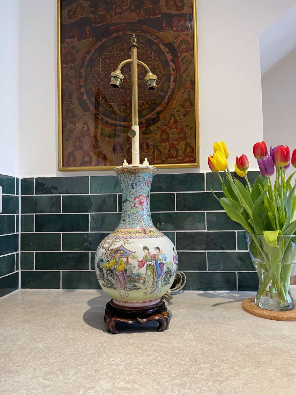 A Chinese Famille Rose porcelain vase mounted as a table lamp with hand-painted figures, floral motifs, brass double sockets, and a carved wooden base.
