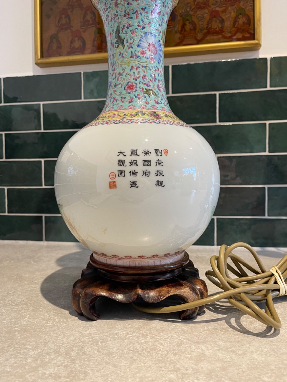 A Chinese Famille Rose porcelain vase mounted as a table lamp with hand-painted figures, floral motifs, brass double sockets, and a carved wooden base. View II