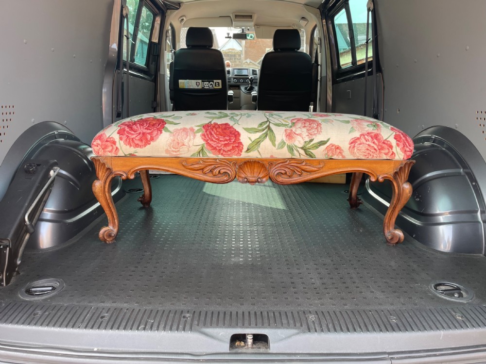 A rectangular Victorian rosewood footstool featuring carved cabriole legs, a shell apron motif, and floral upholstery in pink and red tones.