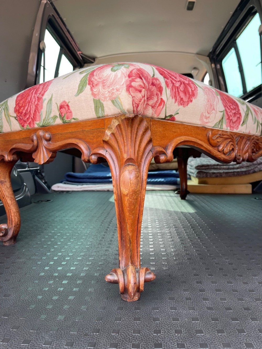 A rectangular Victorian rosewood footstool featuring carved cabriole legs, a shell apron motif, and floral upholstery in pink and red tones. View II