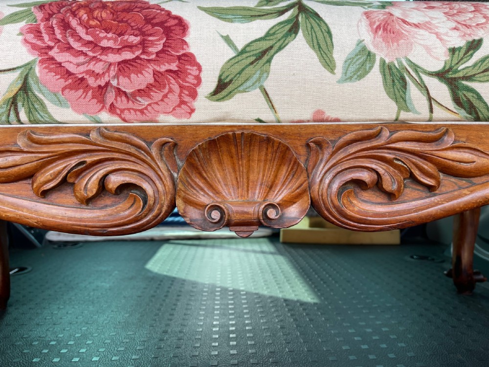 A rectangular Victorian rosewood footstool featuring carved cabriole legs, a shell apron motif, and floral upholstery in pink and red tones. View V