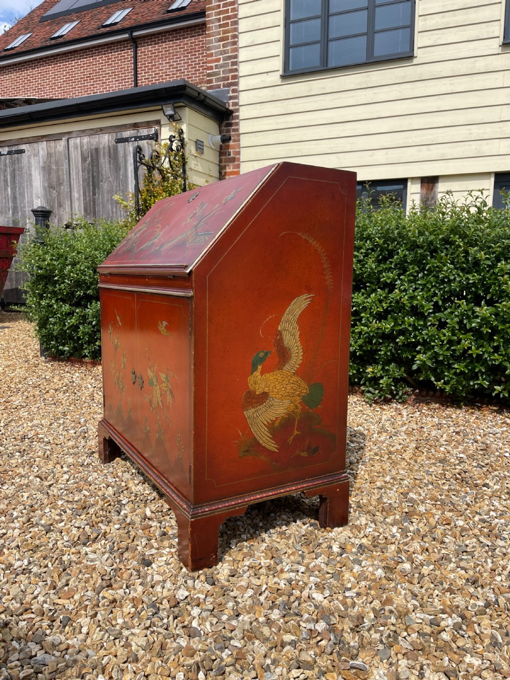 An antique red lacquered fall-front bureau with hand-painted Chinoiserie scenes and a yellow fitted interior featuring cubbies and small drawers. View III