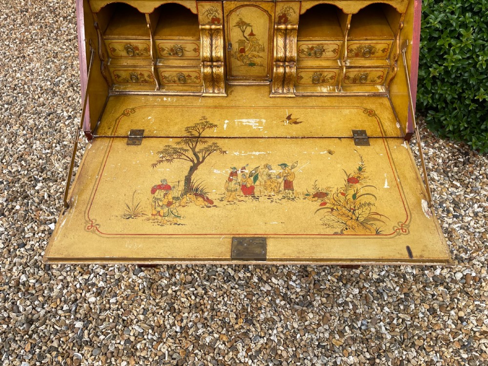 An antique red lacquered fall-front bureau with hand-painted Chinoiserie scenes and a yellow fitted interior featuring cubbies and small drawers. View XV