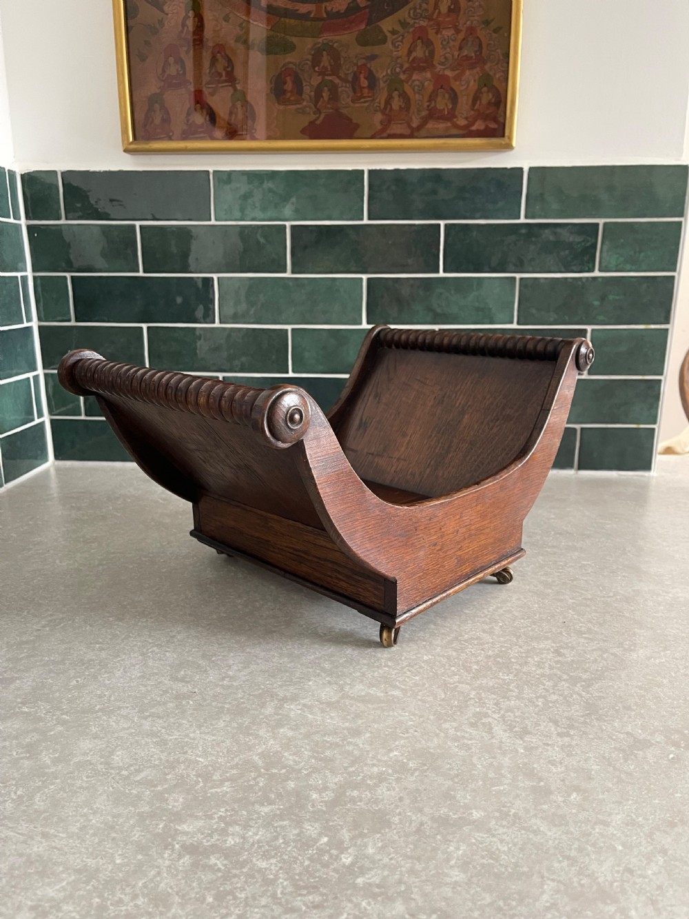 A dark oak Georgian cheese coaster with crescent-shaped sides, turned gadrooned rails, and small brass castors on the base.