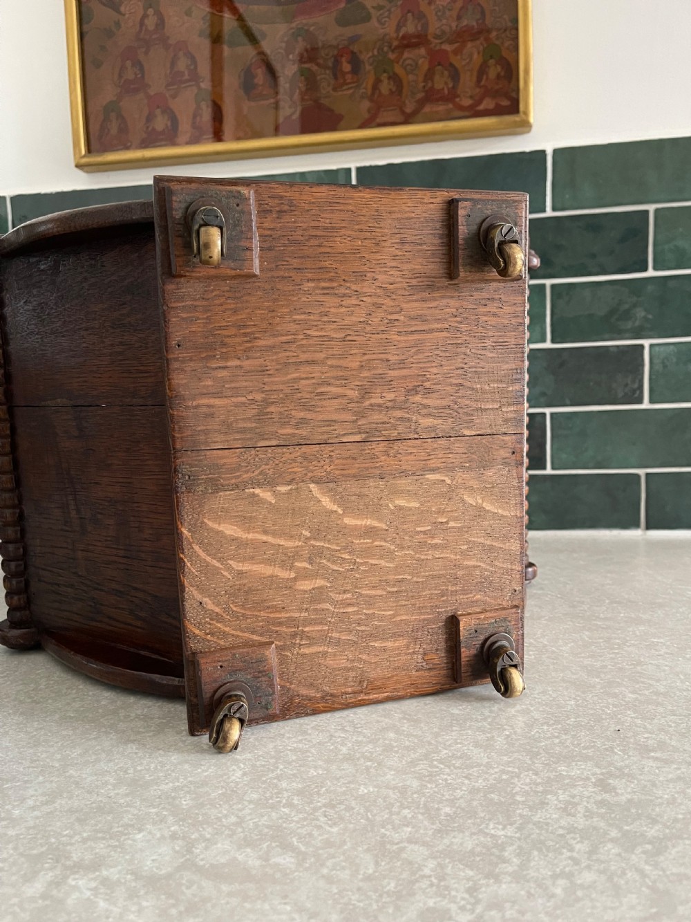 A dark oak Georgian cheese coaster with crescent-shaped sides, turned gadrooned rails, and small brass castors on the base. View III