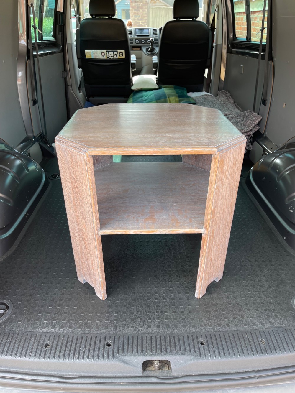 A 1930s Heals style limed oak book table featuring an octagonal top, lower open shelf, and angled slab legs with a chalky grain finish. View VI