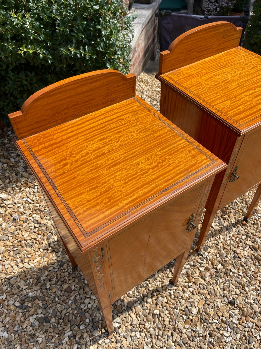 A pair of Edwardian satinwood bedside cupboards featuring diamond marquetry door panels, hand-painted floral stiles, and square tapered legs. View V