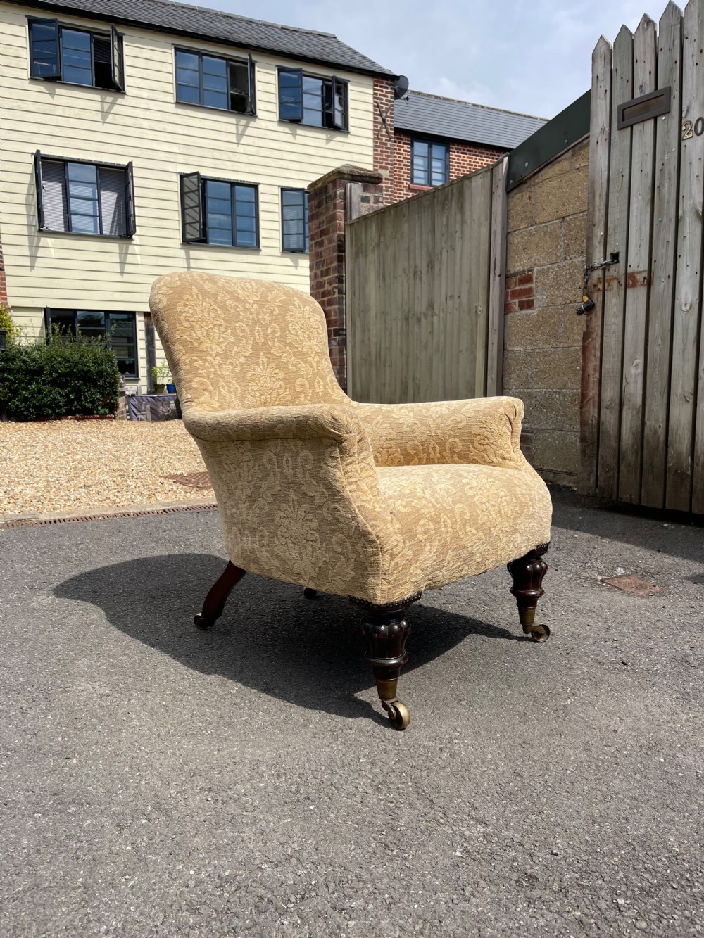 A nineteenth-century spoon back armchair upholstered in gold patterned damask fabric with turned dark timber front legs on brass castors.