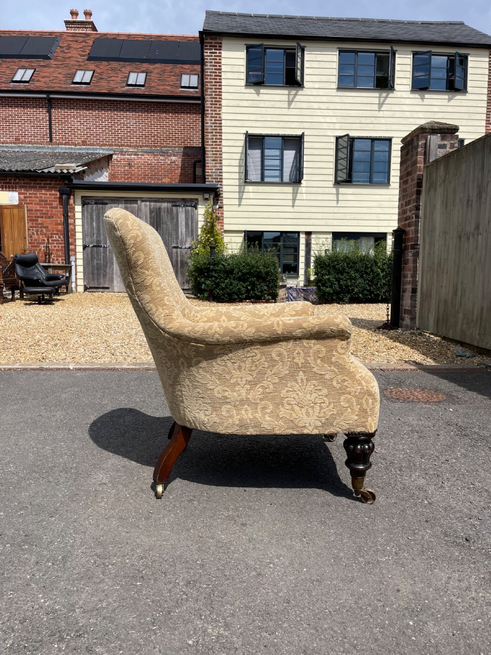 A nineteenth-century spoon back armchair upholstered in gold patterned damask fabric with turned dark timber front legs on brass castors. View II