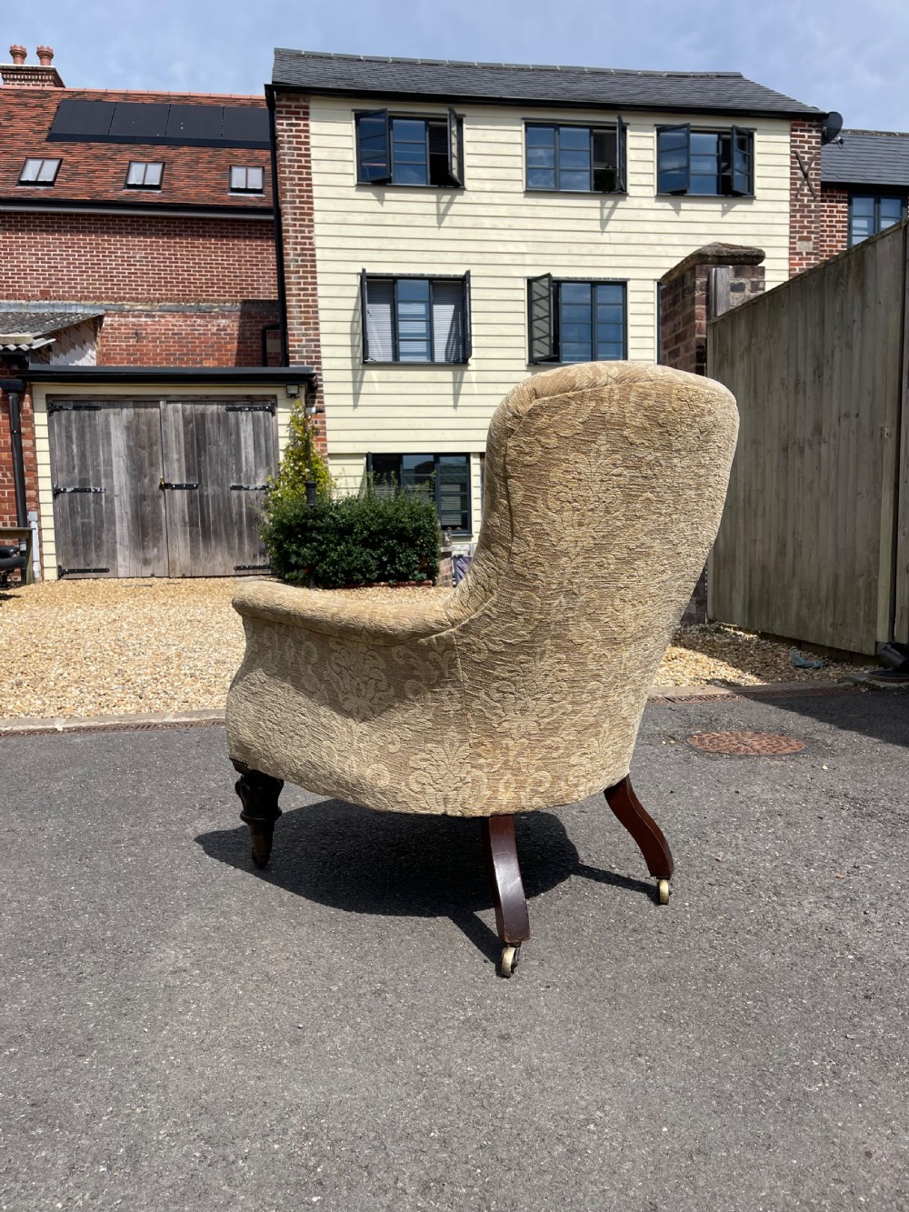 A nineteenth-century spoon back armchair upholstered in gold patterned damask fabric with turned dark timber front legs on brass castors. View III