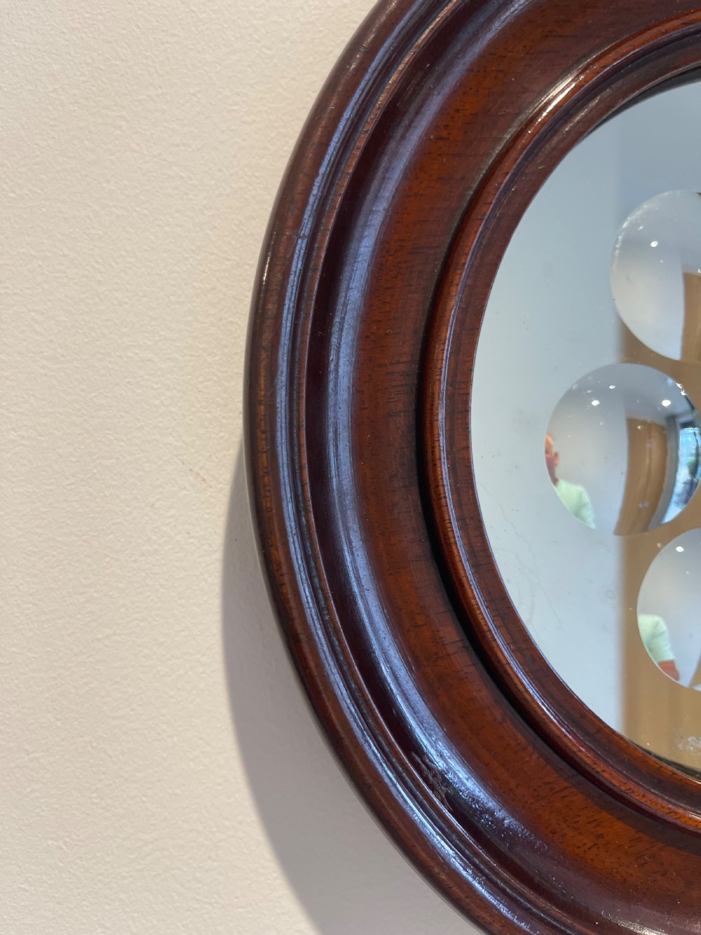 A circular dark mahogany framed wall mirror featuring a central reflective pane set with eight ground circular convex lenses. View III
