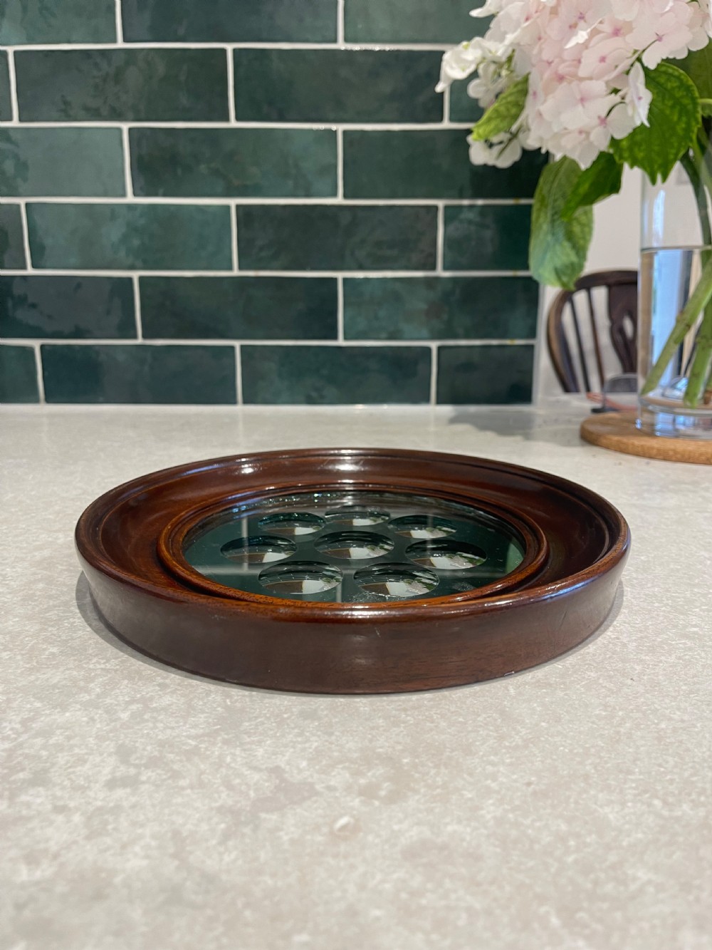 A circular dark mahogany framed wall mirror featuring a central reflective pane set with eight ground circular convex lenses. View IV