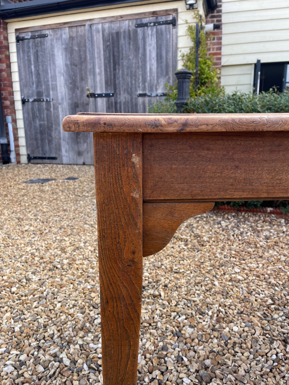 A long antique elm refectory table featuring a natural wood grain finish, straight legs, and end stretchers. View VII