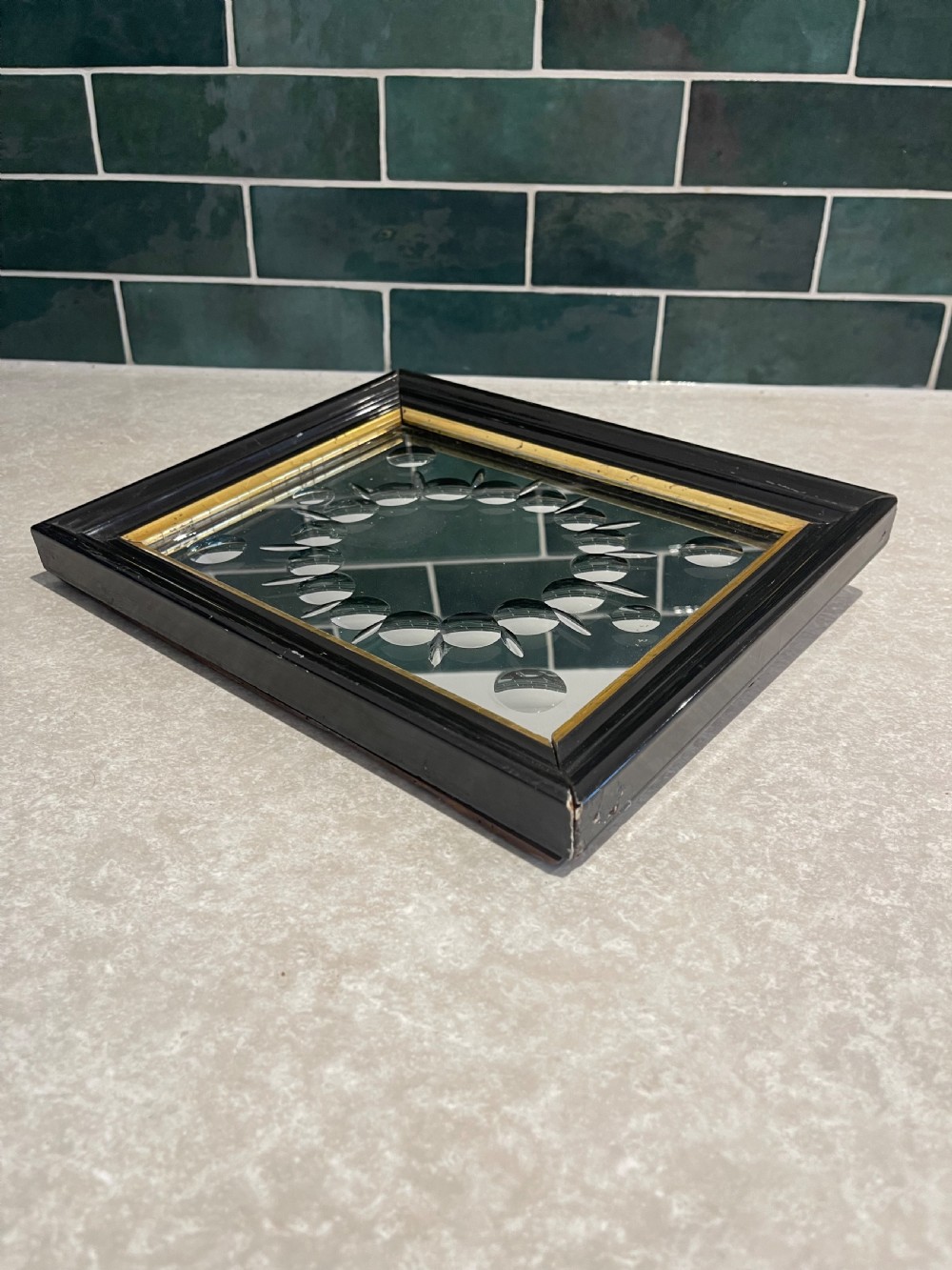 A rectangular black ebonised wall mirror featuring a gold gilt inner moulding and a central ring of circular convex glass cabochons. View III