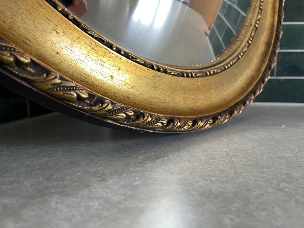 A large circular giltwood convex mirror featuring a carved moulded frame with repeating foliage detail. View III
