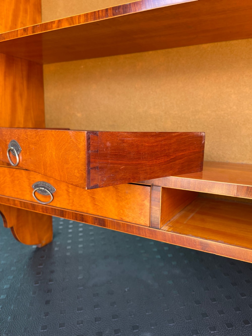 An antique satinwood hanging shelf unit featuring an arched cresting rail, three open tiers, and two drawers at the base with brass drop ring handles. View III