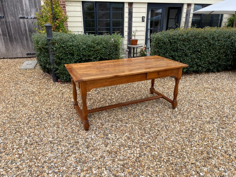 A nineteenth-century rectangular cherrywood table featuring a single frieze drawer, turned legs, and an H-stretcher base.