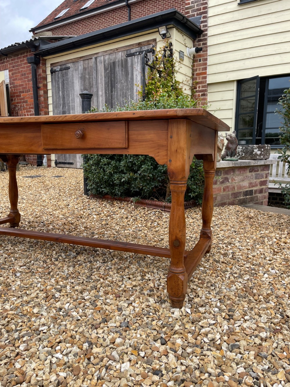 A nineteenth-century rectangular cherrywood table featuring a single frieze drawer, turned legs, and an H-stretcher base. View III