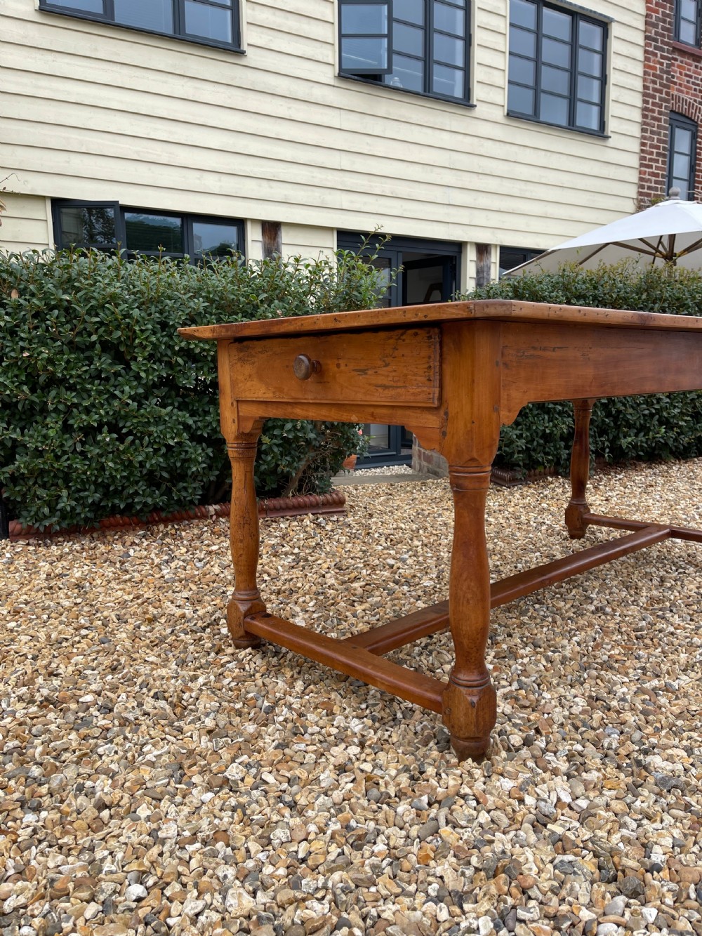 A nineteenth-century rectangular cherrywood table featuring a single frieze drawer, turned legs, and an H-stretcher base. View V