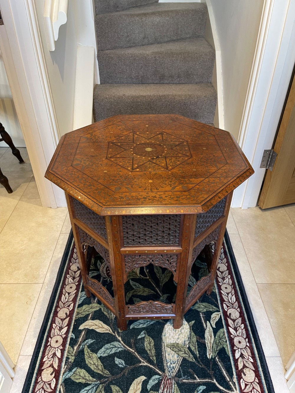 An octagonal Anglo-Indian side table featuring intricate geometric brass inlay on top and carved jali lattice apron panels.