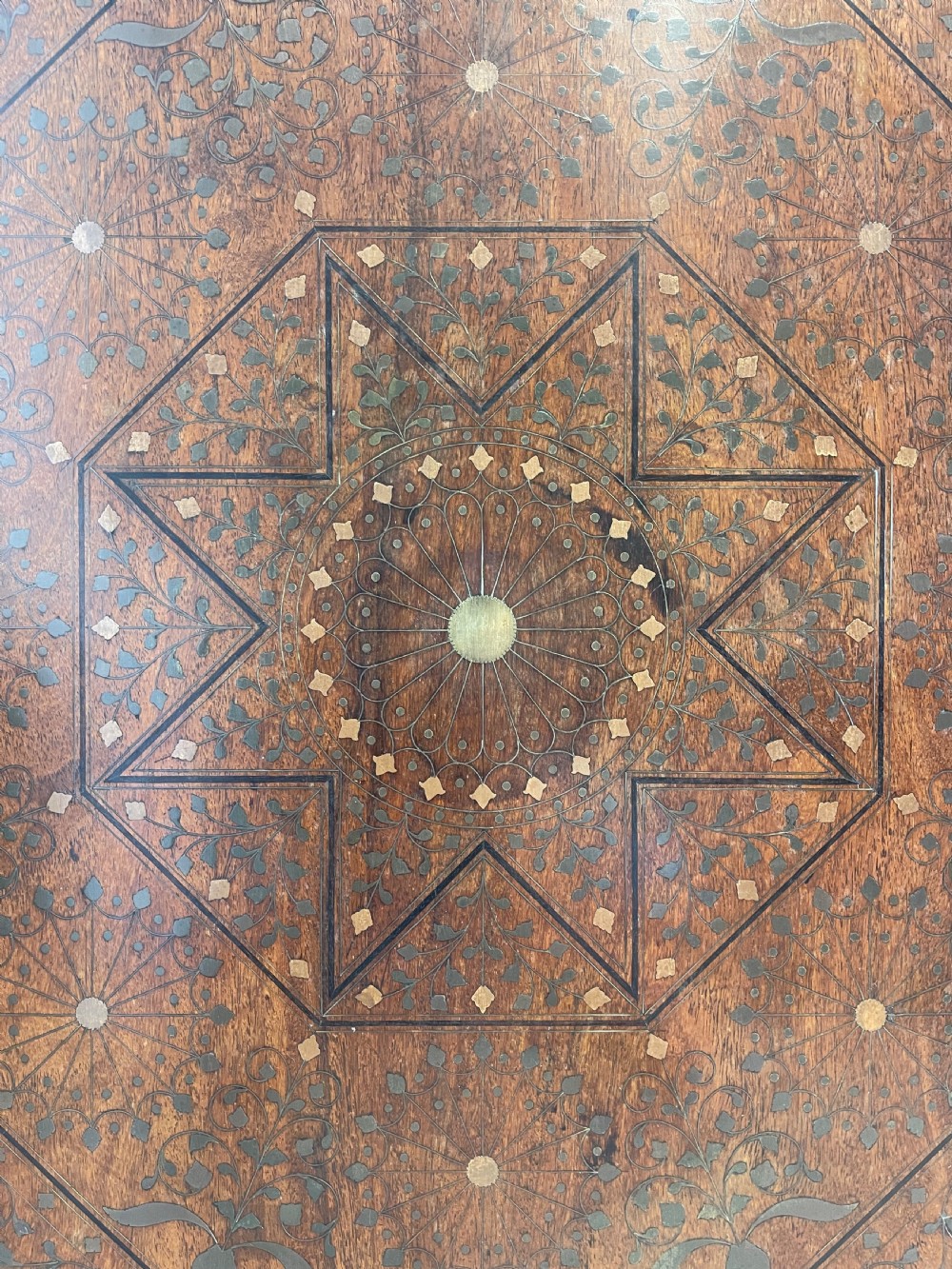 An octagonal Anglo-Indian side table featuring intricate geometric brass inlay on top and carved jali lattice apron panels. View VI