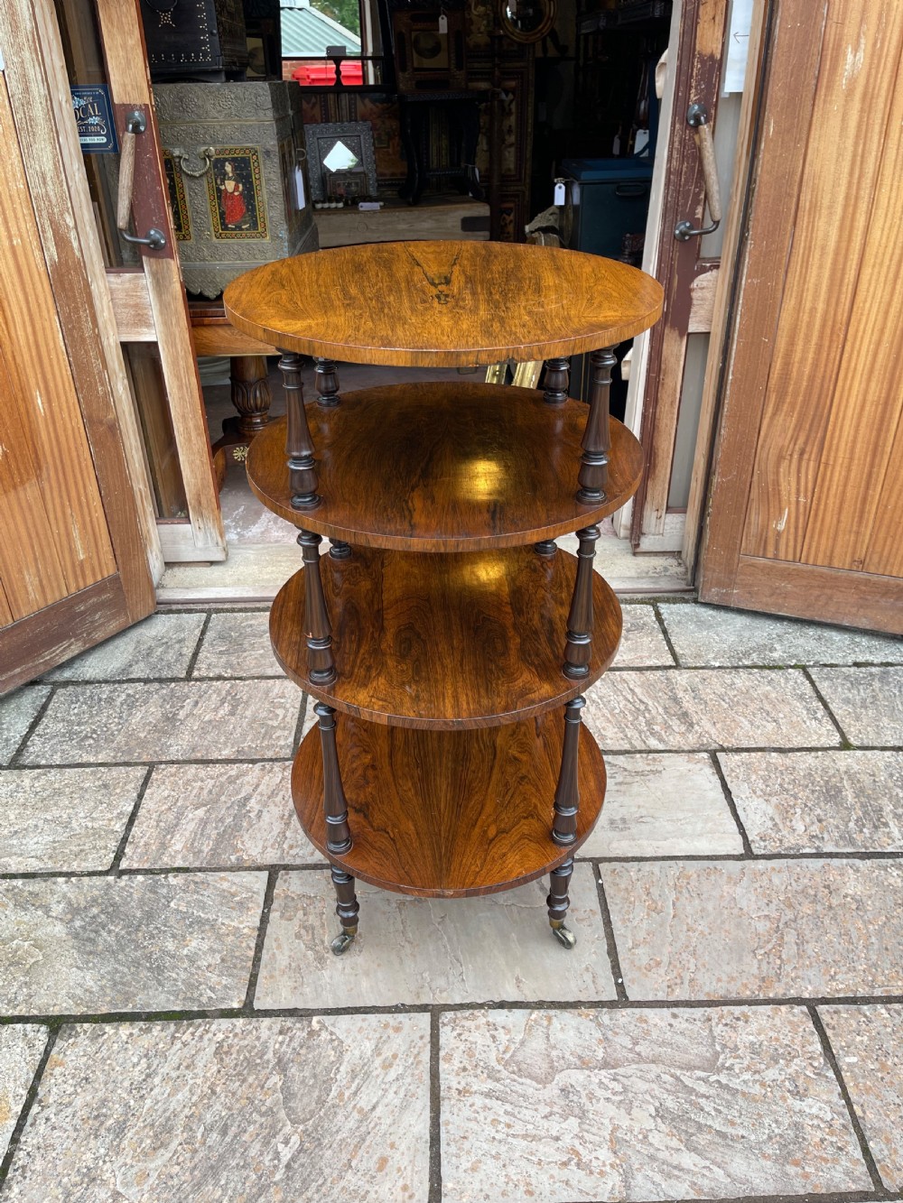 A 19th-century circular rosewood whatnot featuring four open tiers supported by turned columns and set on brass castors.