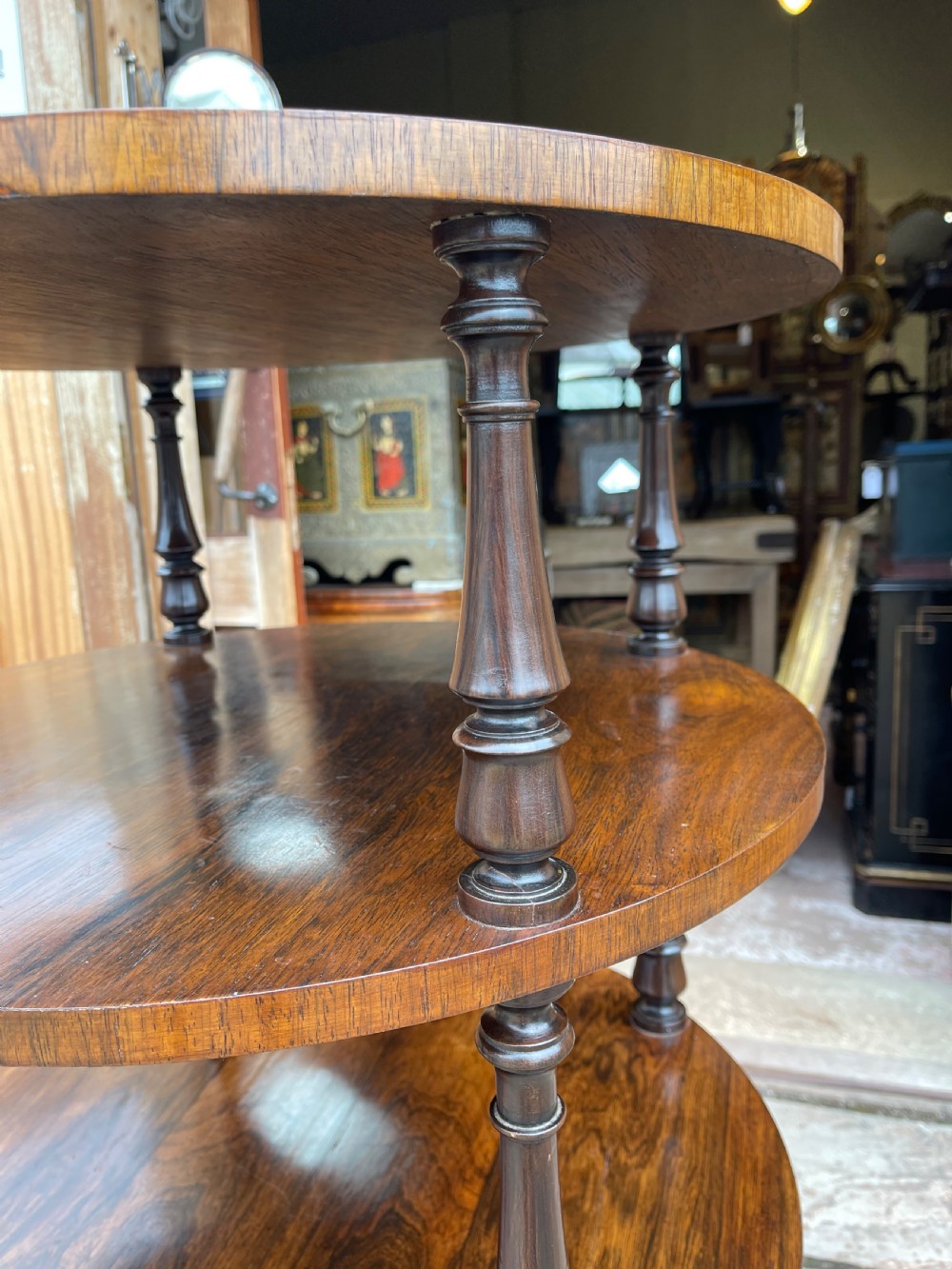 A 19th-century circular rosewood whatnot featuring four open tiers supported by turned columns and set on brass castors. View II