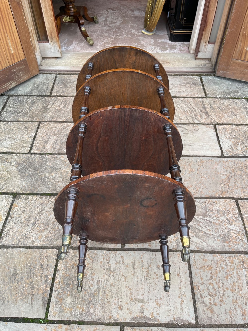 A 19th-century circular rosewood whatnot featuring four open tiers supported by turned columns and set on brass castors. View VII
