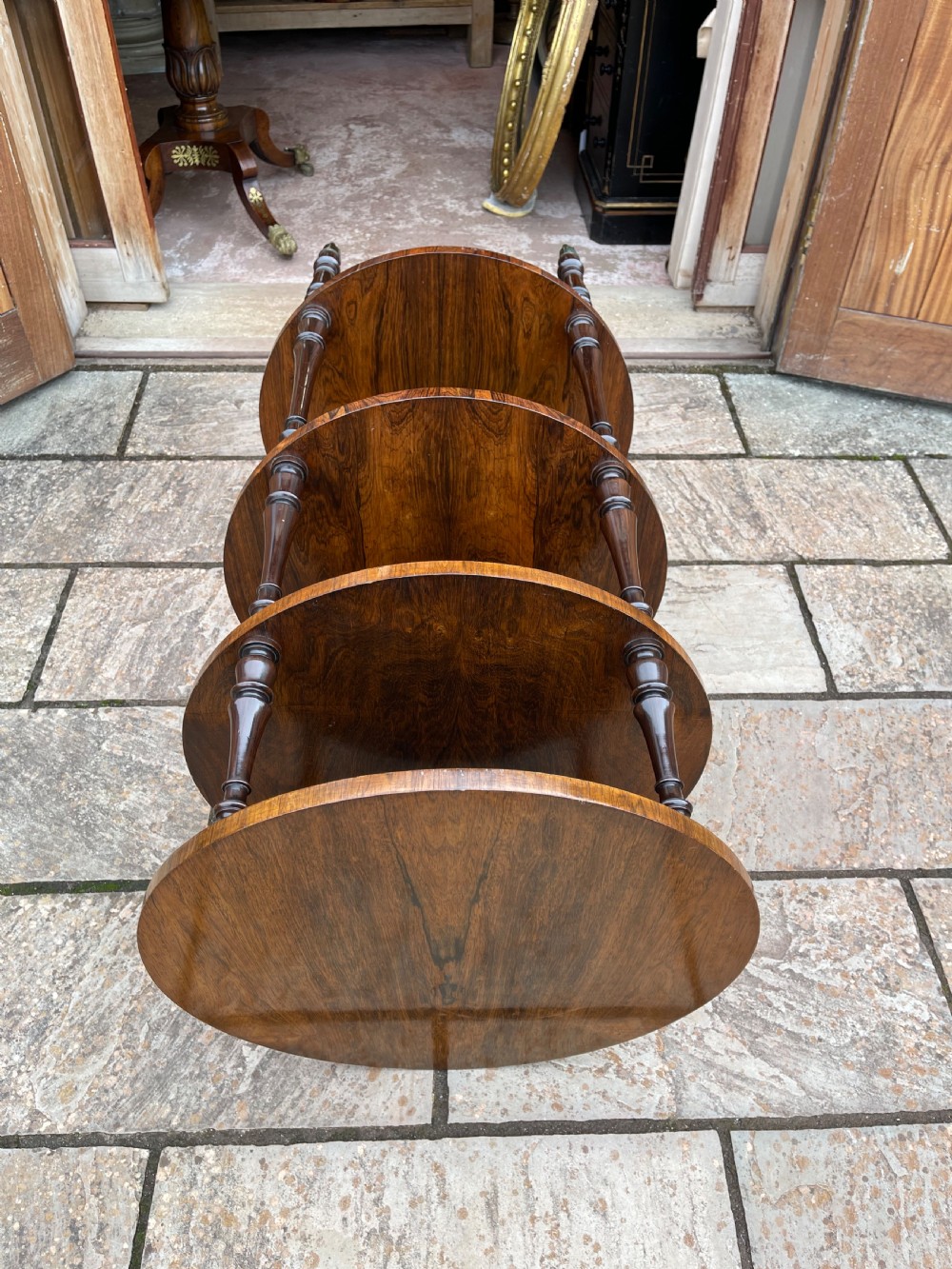 A 19th-century circular rosewood whatnot featuring four open tiers supported by turned columns and set on brass castors. View VIII