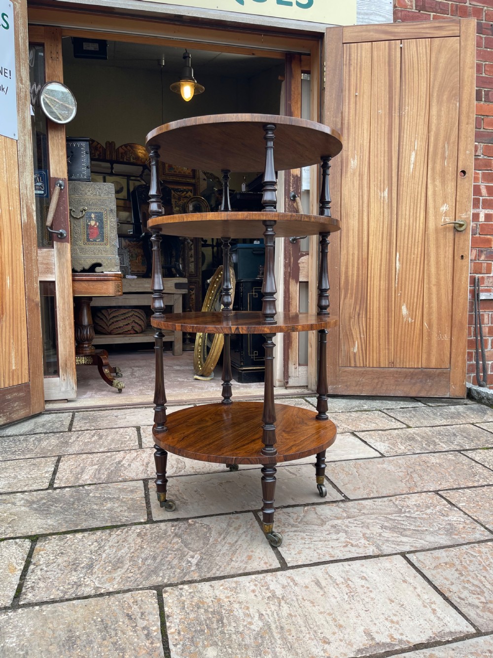 A 19th-century circular rosewood whatnot featuring four open tiers supported by turned columns and set on brass castors. View IX