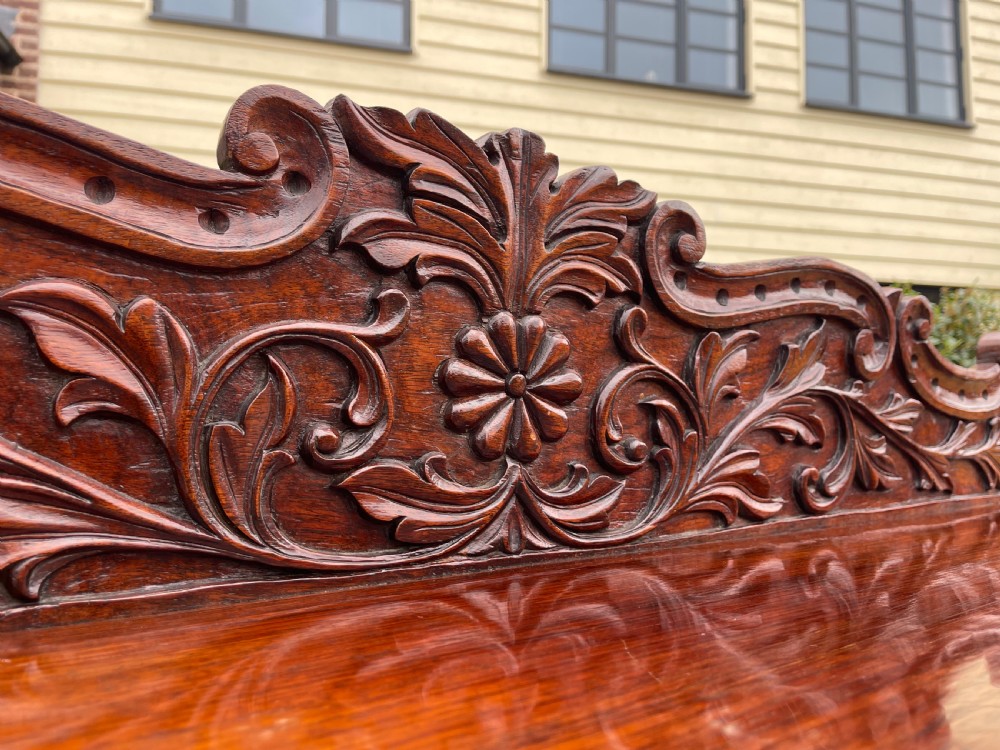 An ornate carved dark rosewood console table featuring an elaborate scrollwork backboard, shaped top, and intricately carved cabriole legs with stretchers. View II