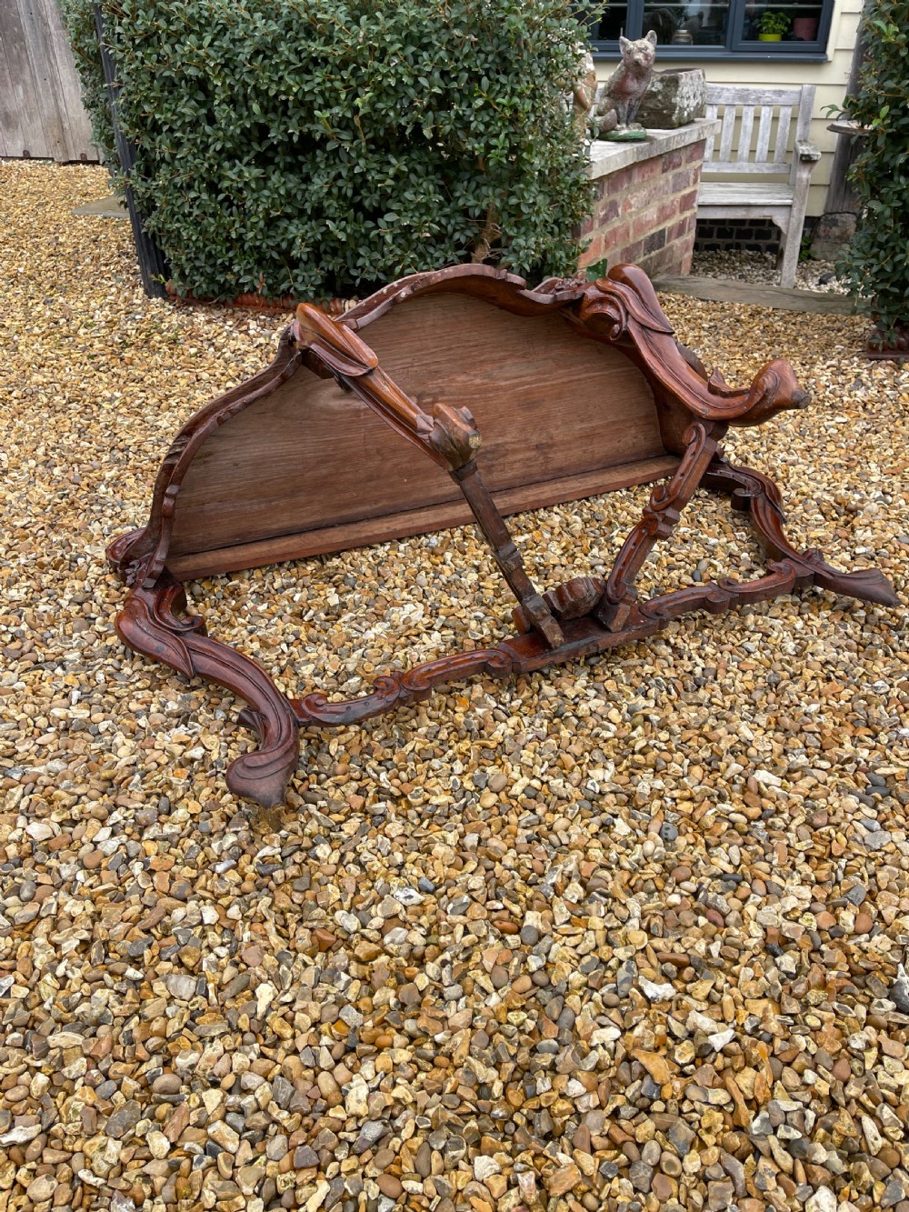 An ornate carved dark rosewood console table featuring an elaborate scrollwork backboard, shaped top, and intricately carved cabriole legs with stretchers. View III
