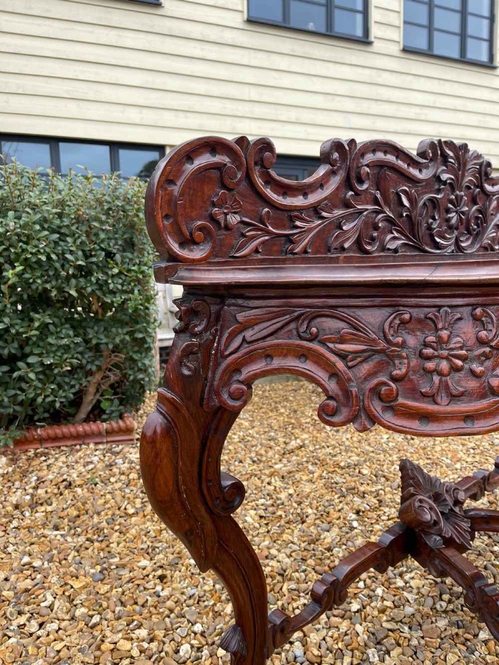 An ornate carved dark rosewood console table featuring an elaborate scrollwork backboard, shaped top, and intricately carved cabriole legs with stretchers. View VIII