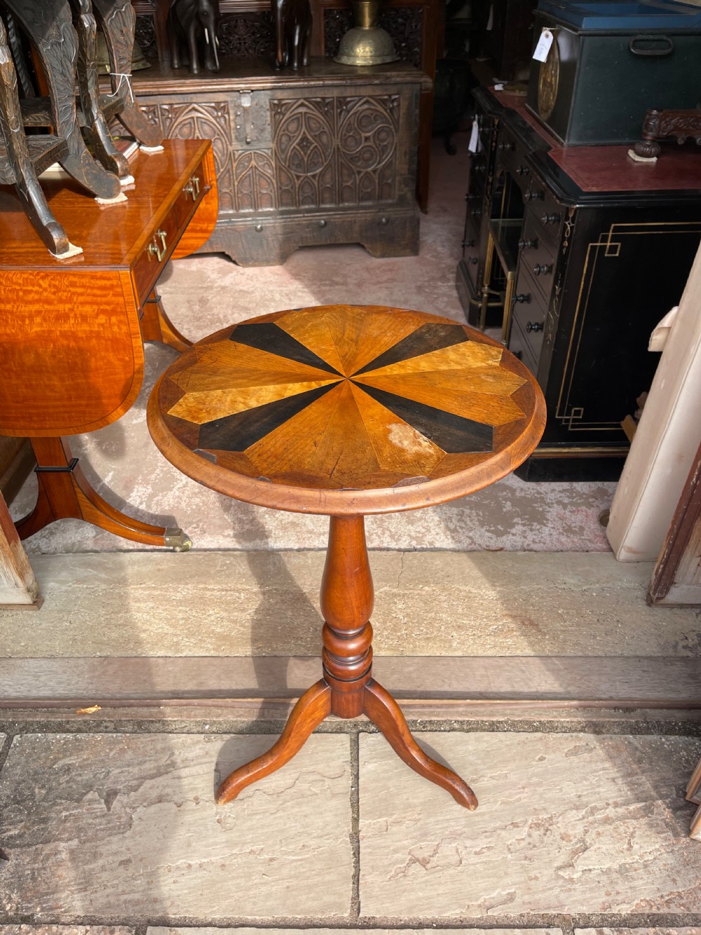 A circular Victorian specimen timber occasional table featuring a starburst parquetry top, a turned central pedestal stem, and three downswept tripod legs.