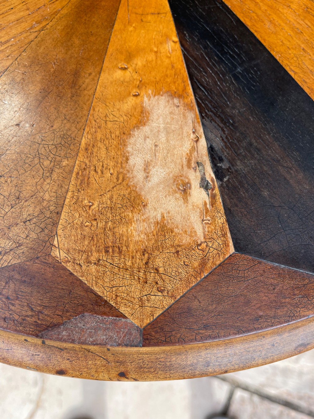 A circular Victorian specimen timber occasional table featuring a starburst parquetry top, a turned central pedestal stem, and three downswept tripod legs. View III