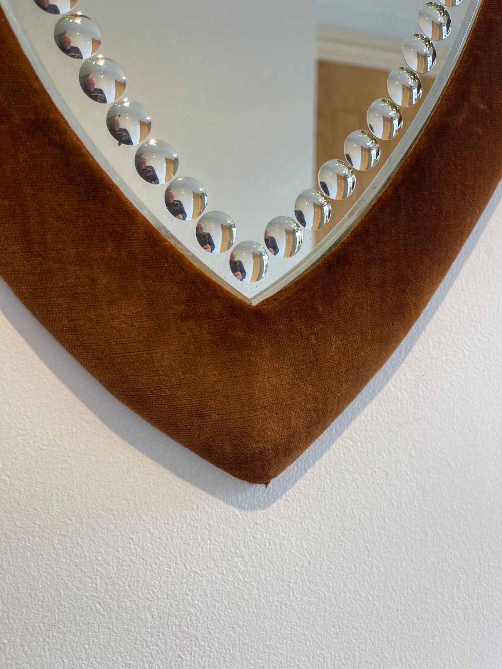 A shield-shaped wall mirror featuring a warm brown velvet fabric frame and an inner border of decorative circular glass beads. View II