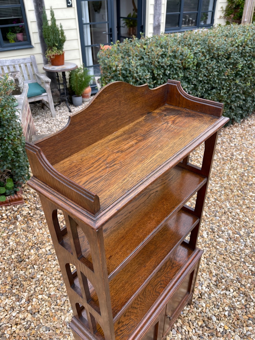 A freestanding oak open bookcase featuring two upper shelves with arched side cutouts over a lower two-door cupboard. View II