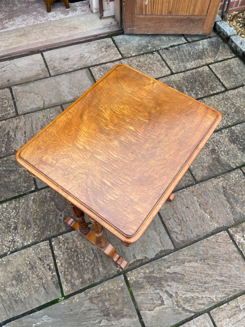 A Victorian burr walnut sewing work table with turned barley twist columns, a pleated green fabric basket, and a carved trestle base. View II