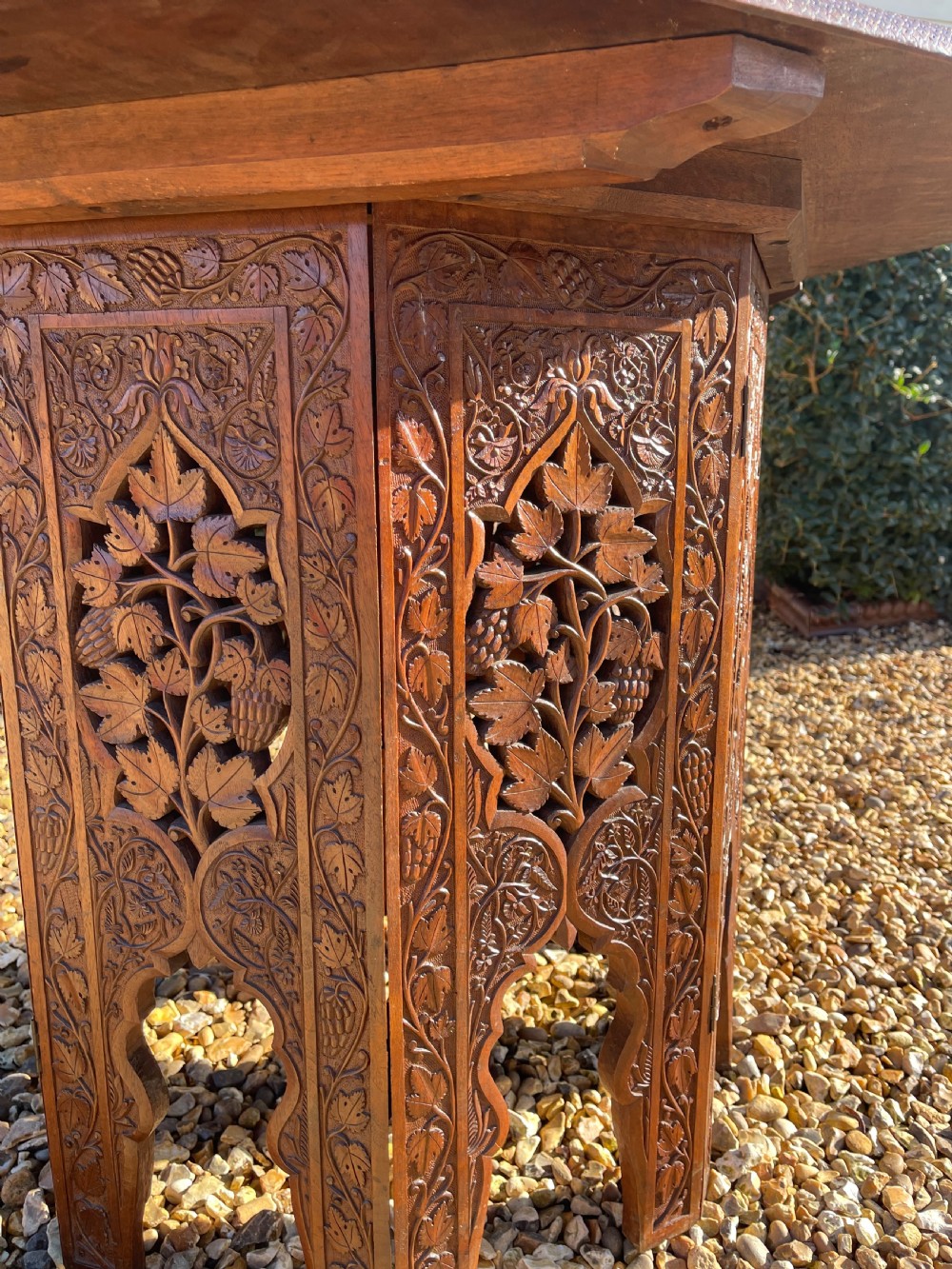 An octagonal dark walnut table featuring detailed botanical relief carving on the tabletop and pierced arched side panels. View III