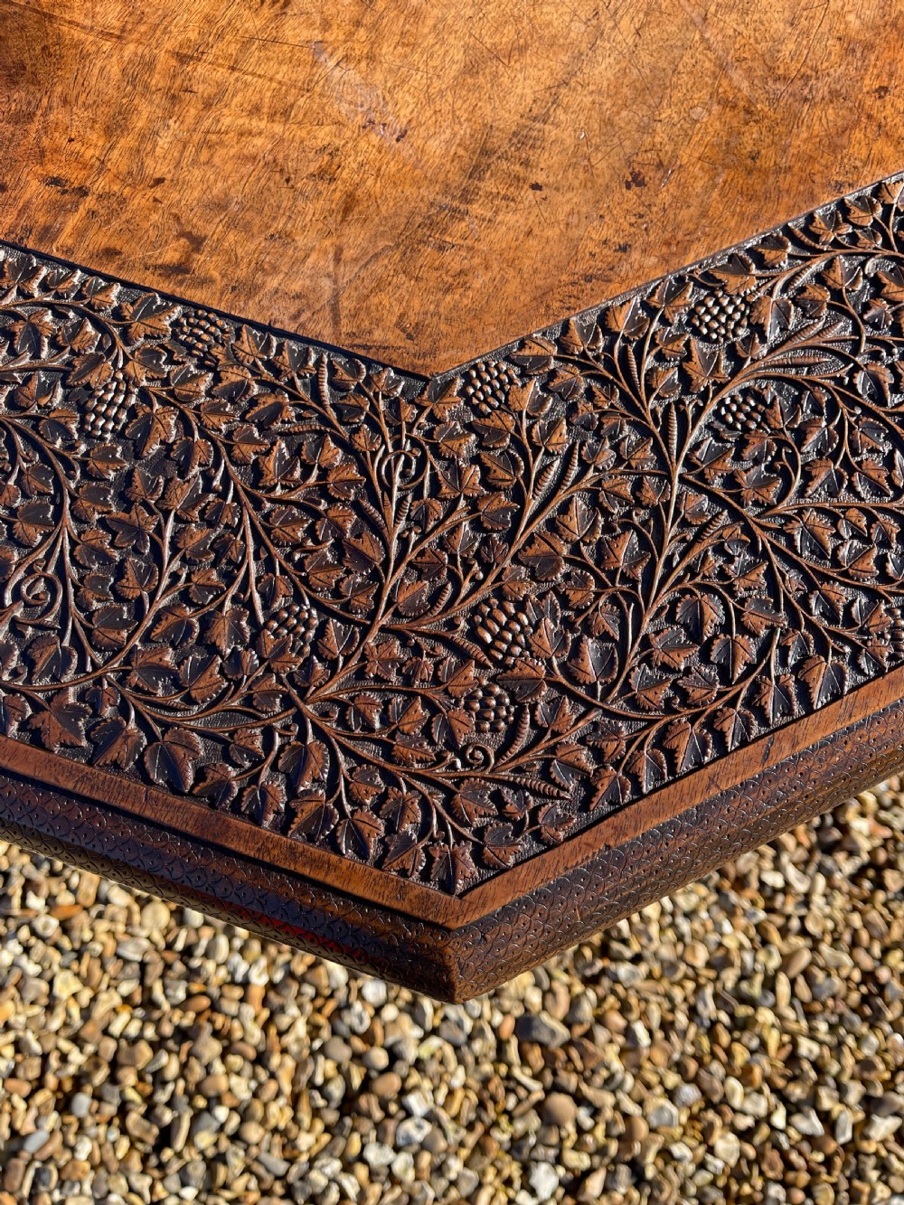 An octagonal dark walnut table featuring detailed botanical relief carving on the tabletop and pierced arched side panels. View VI