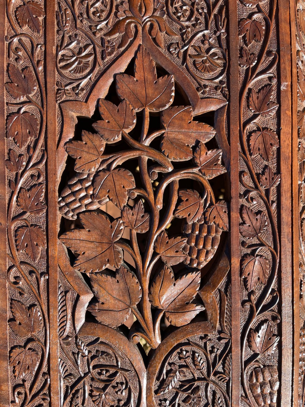 An octagonal dark walnut table featuring detailed botanical relief carving on the tabletop and pierced arched side panels. View VII